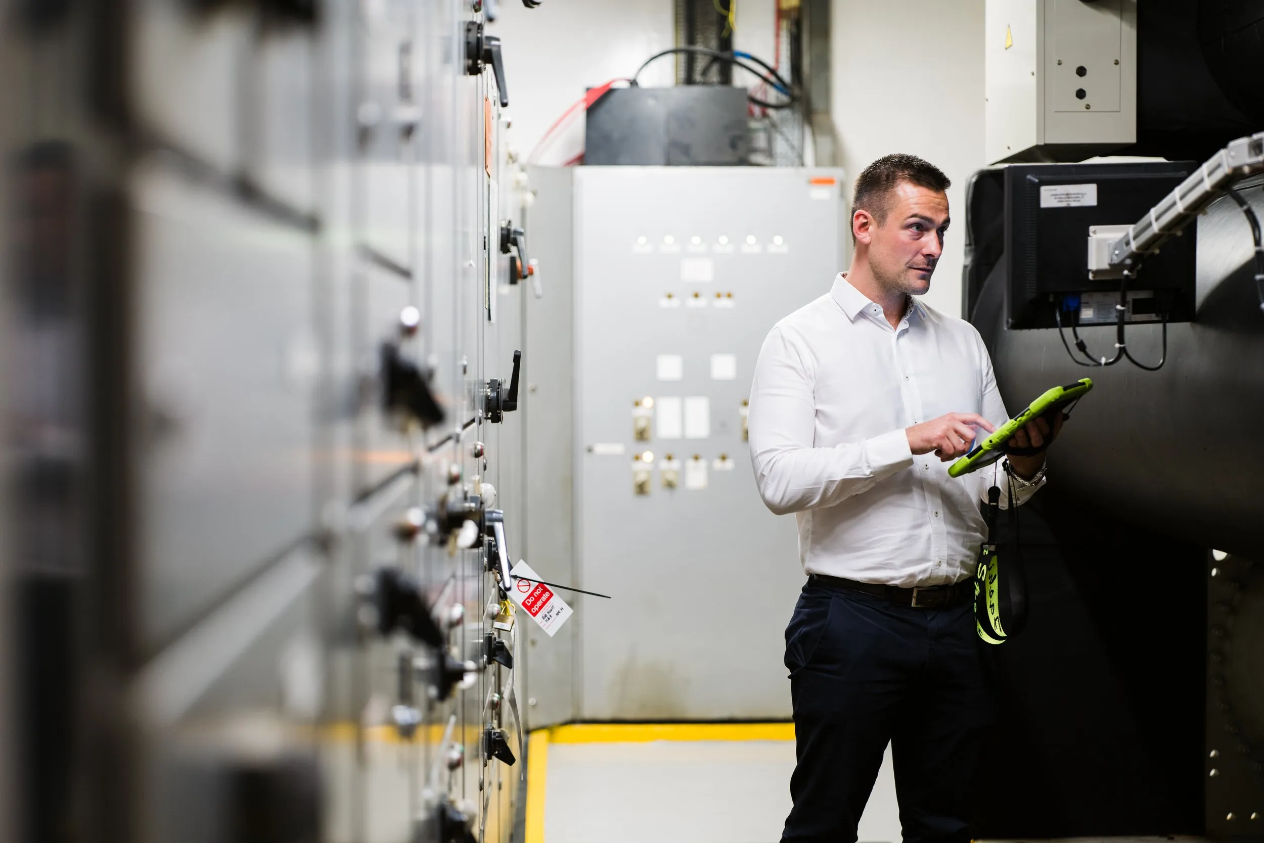 Engineer inspecting electrical switchgear with tablet, industrial branding photography, London