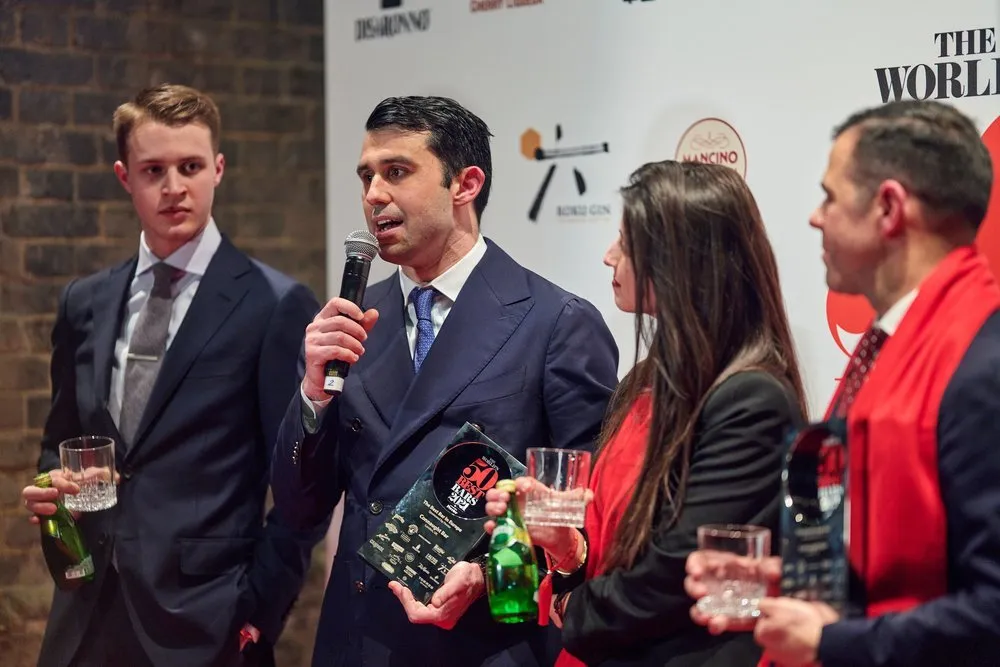 Award winner giving speech at microphone with branded backdrop, London awards photography