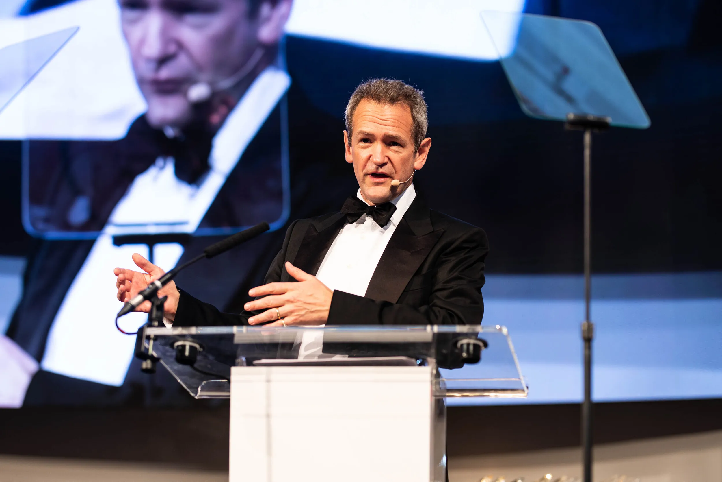 Black tie awards ceremony with presenter at lectern on stage, London
