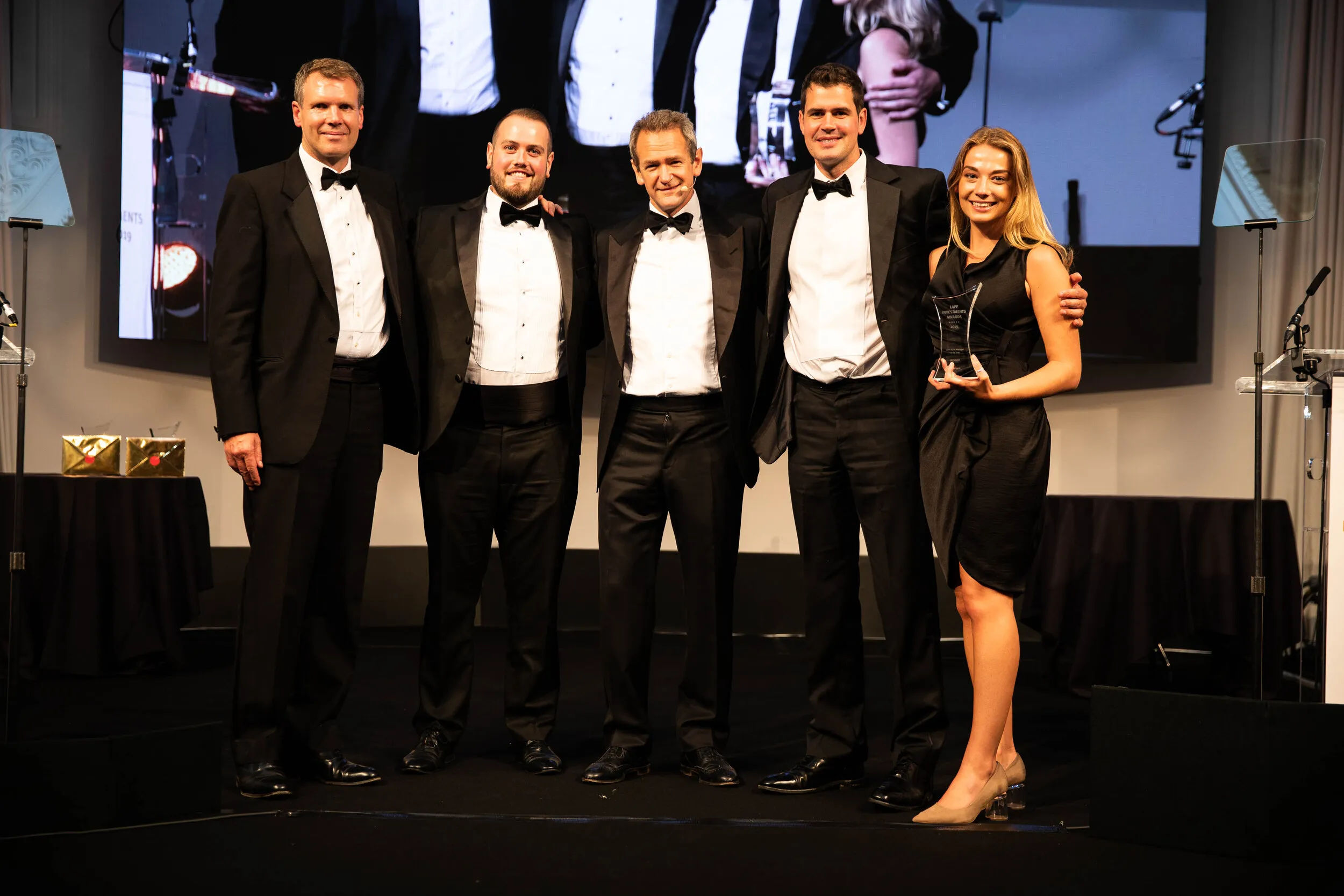Black tie awards group on stage holding trophies, London corporate event photography