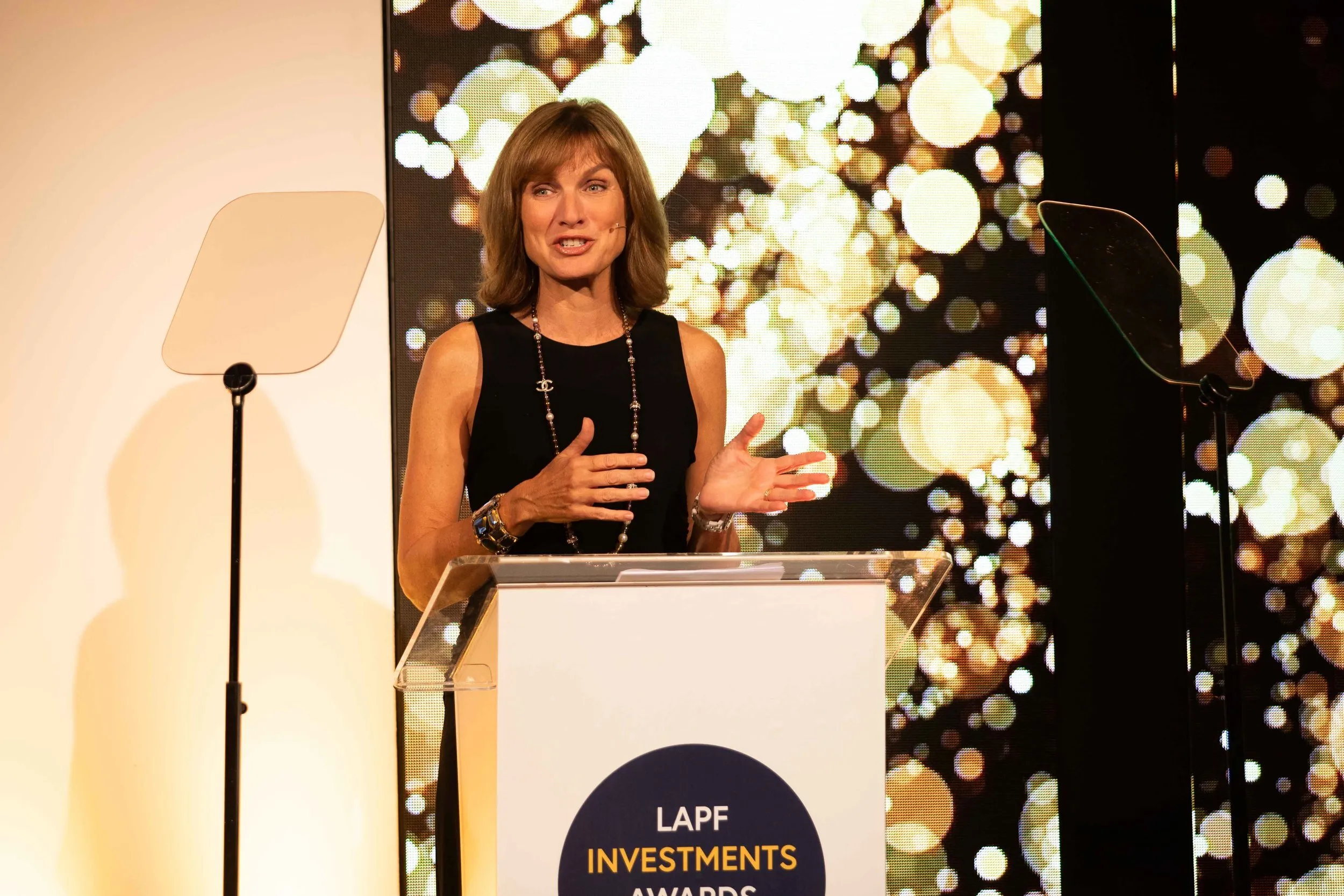 Female host presenting at awards ceremony lectern, corporate event photography London