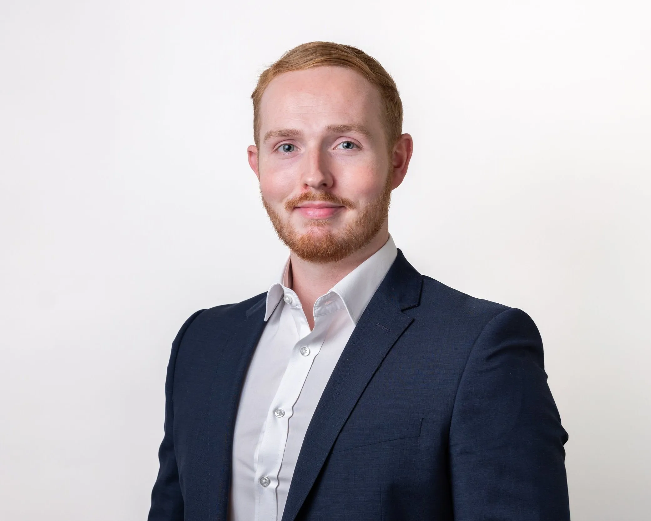 Corporate headshot of man with ginger hair in navy suit, London
