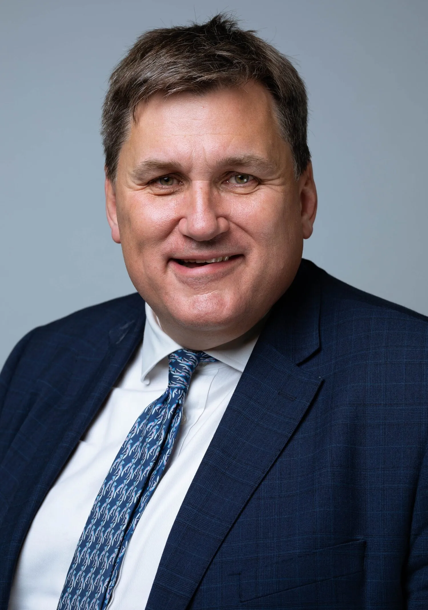 Corporate headshot of man in navy suit with blue tie, London