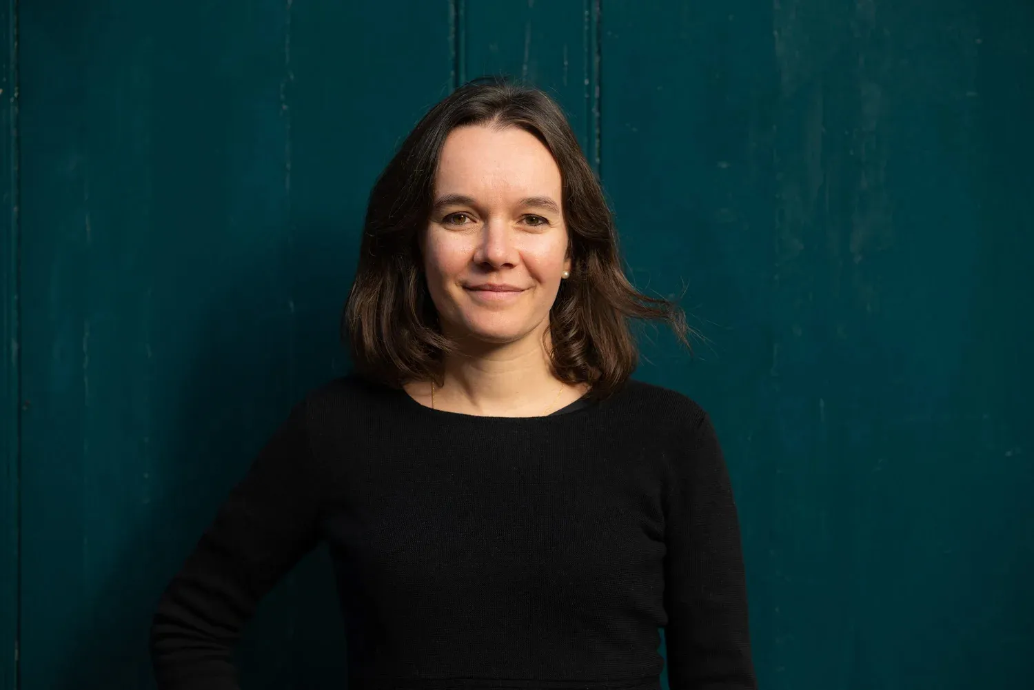 Professional headshot of woman against teal background, natural light, London