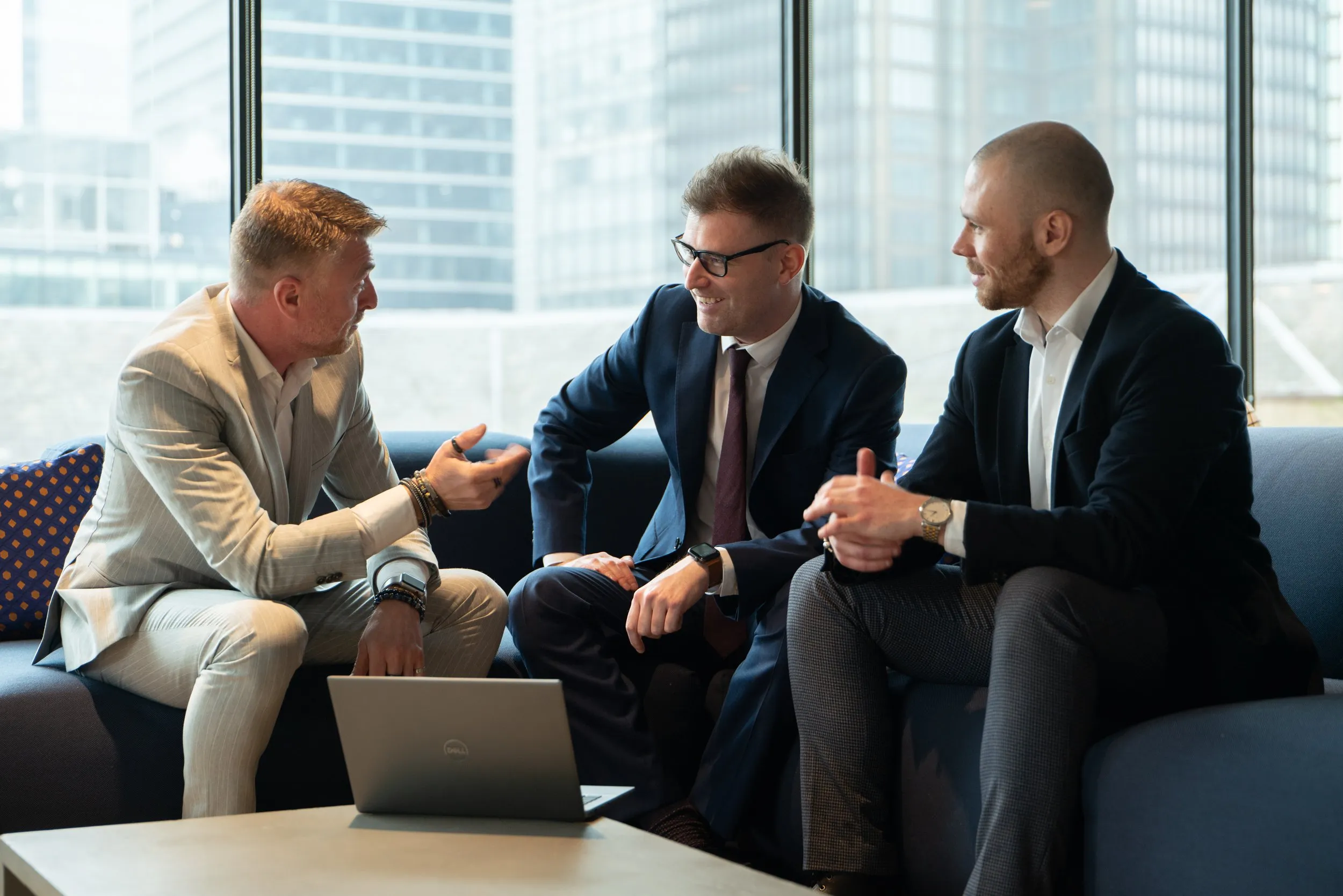 Business meeting on a sofa with City of London skyline and laptop, corporate lifestyle photography