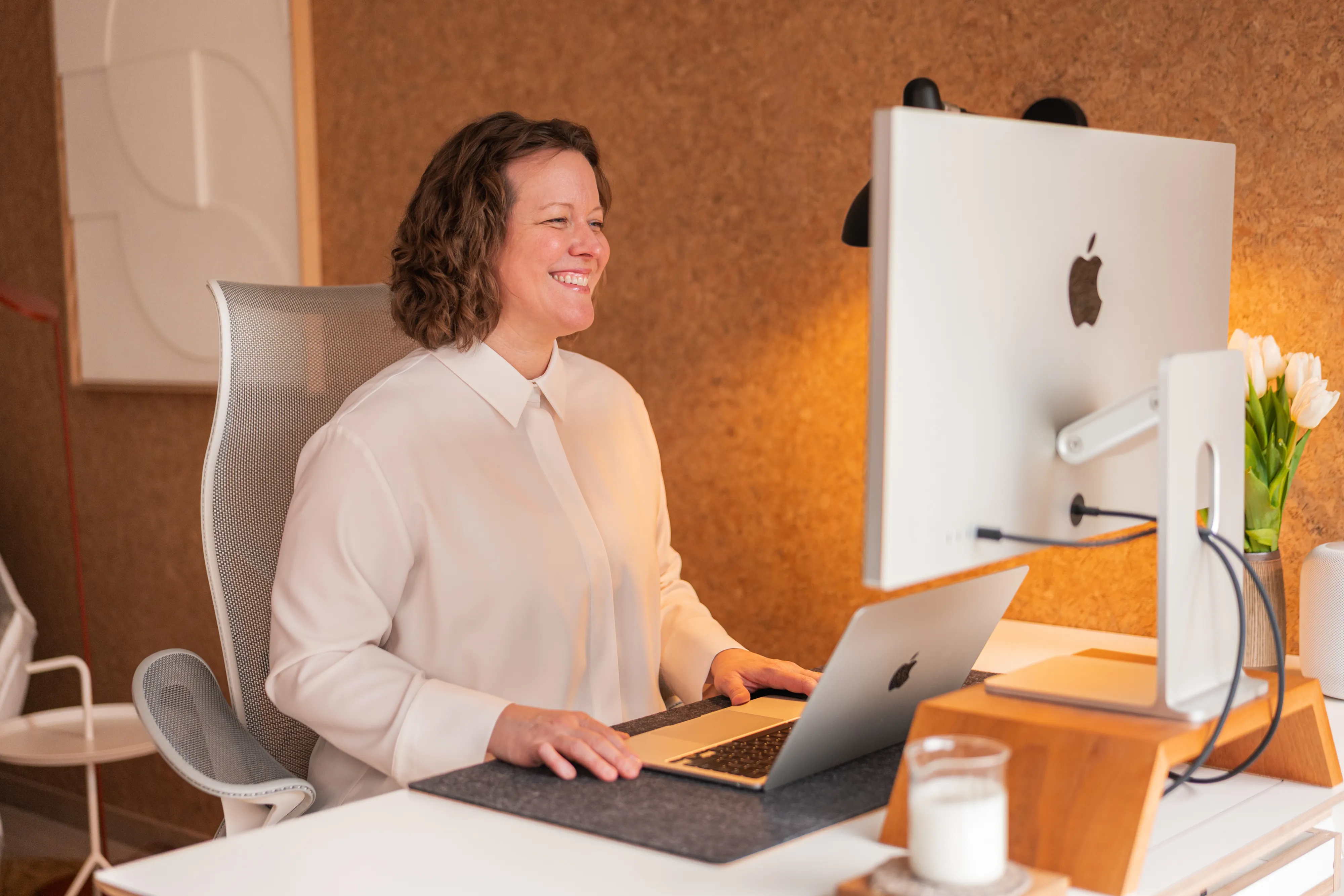 Woman smiling at iMac in a modern London startup office, corporate lifestyle photography