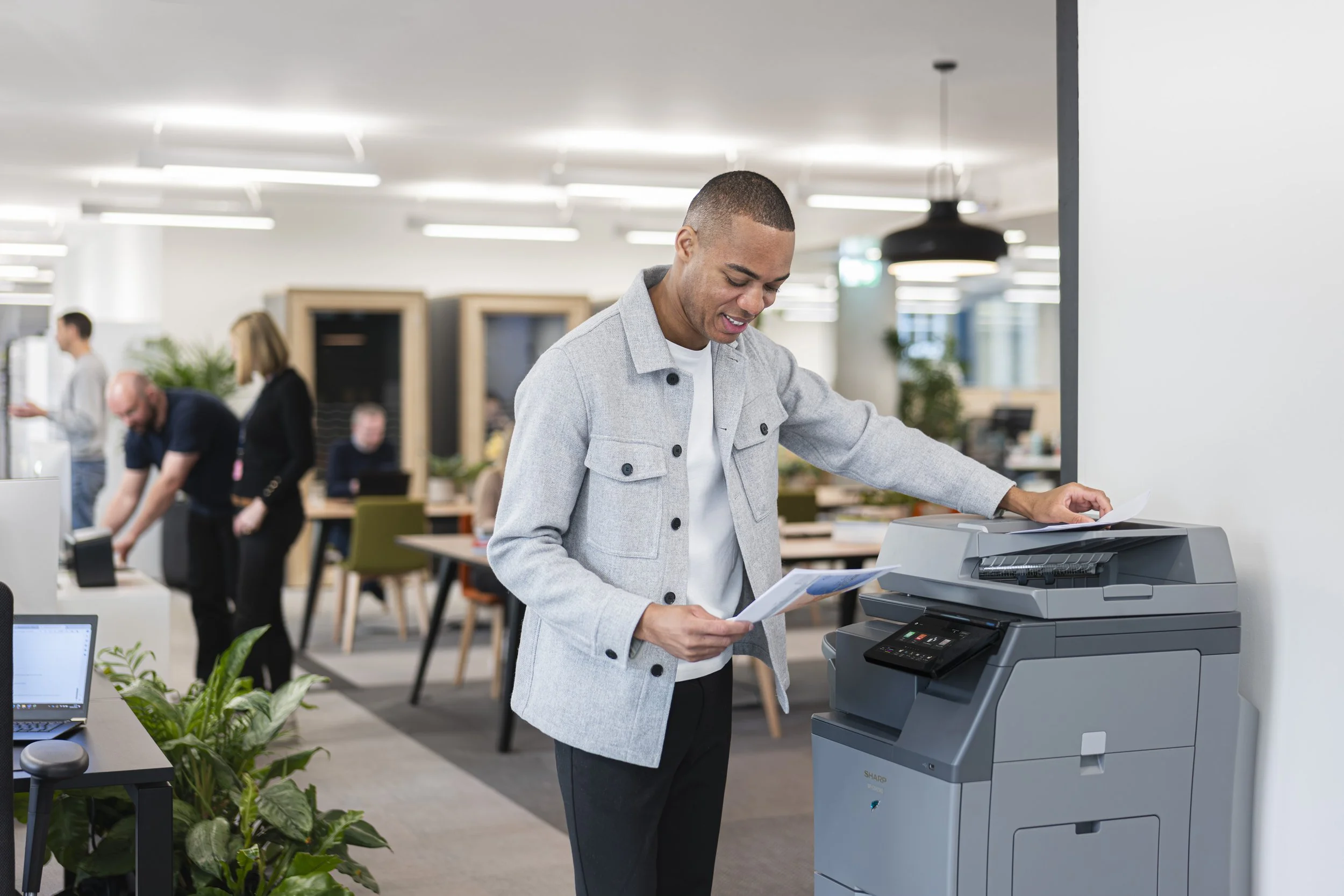 Final delivered image — Sharp Electronics corporate lifestyle photography, talent at multifunction printer in London open-plan office